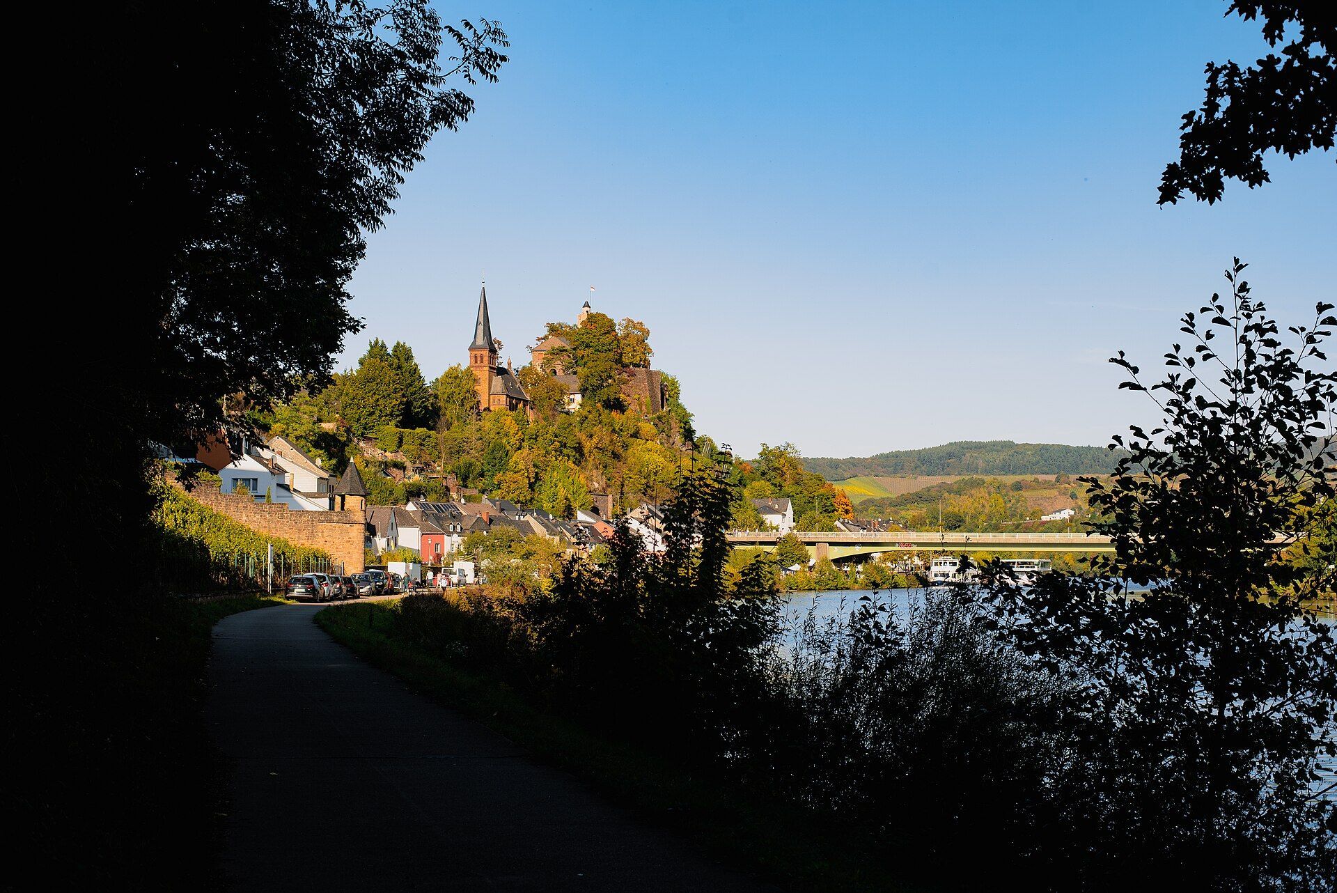Blick von Süden die Saar entlang auf Saarburg mit Evangelischer Kirche, Burg und Altstadtbrücke, Oktoberlicht